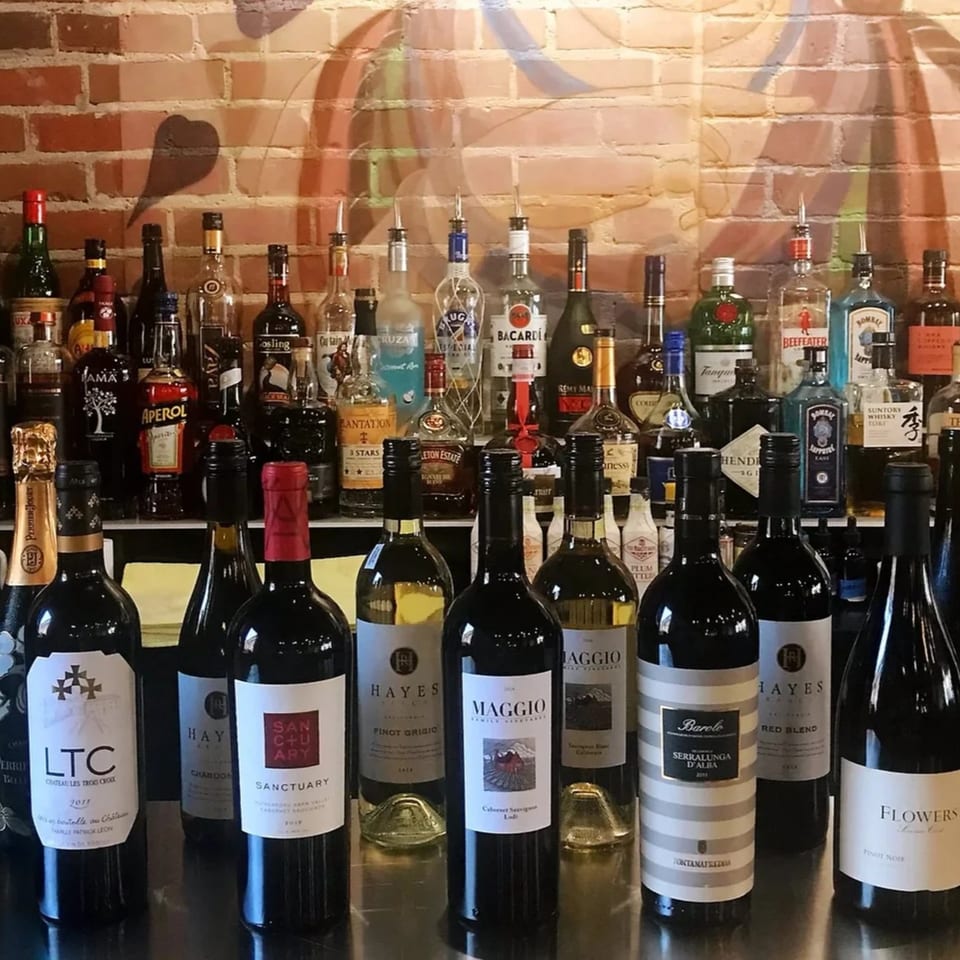 A bar at Heavenly Asian Cuisine & Lounge with a wide selection of liquor and wine bottles.