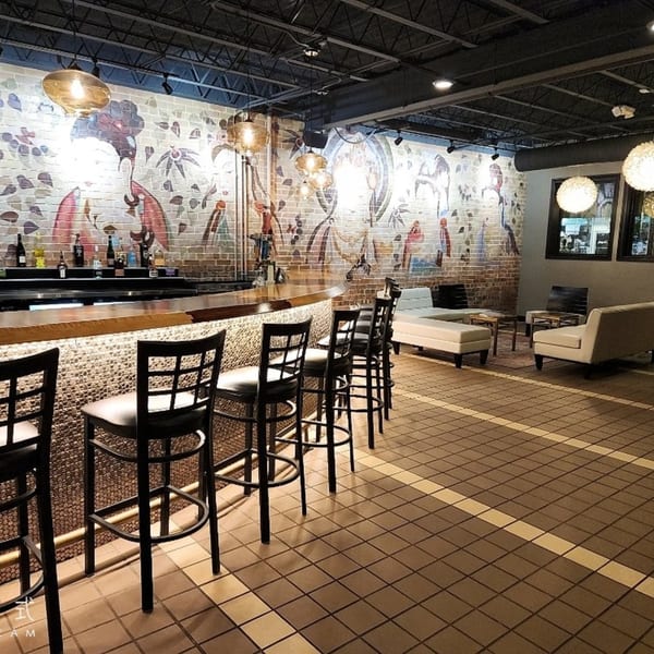 Heavenly Asian Cuisine & Lounge bar area with stools, bottles, and a brick wall mural.