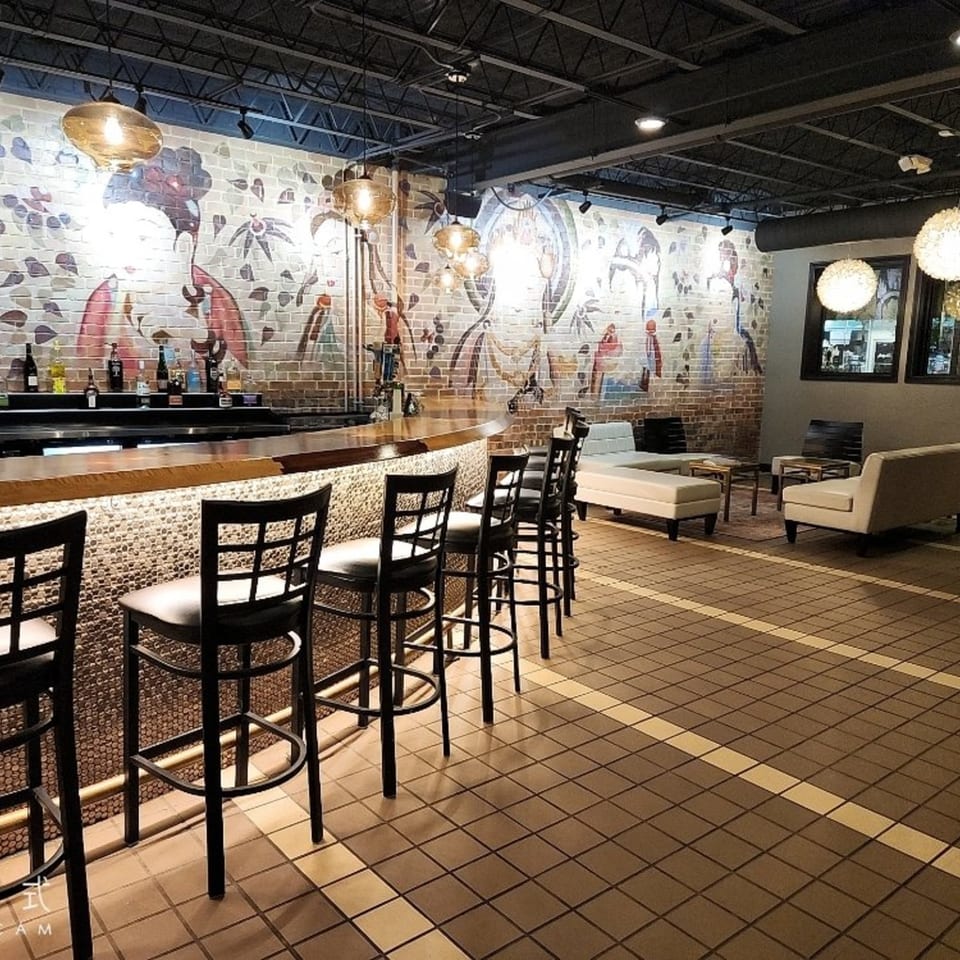 Heavenly Asian Cuisine & Lounge bar area with stools, bottles, and a brick wall mural.
